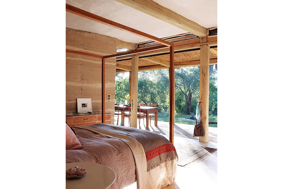 Perfect Hideaways real estate property: An open plan bedroom with natural wood and earth tones, featuring a four-poster bed and minimal decor. Otto House, Okavango Delta.