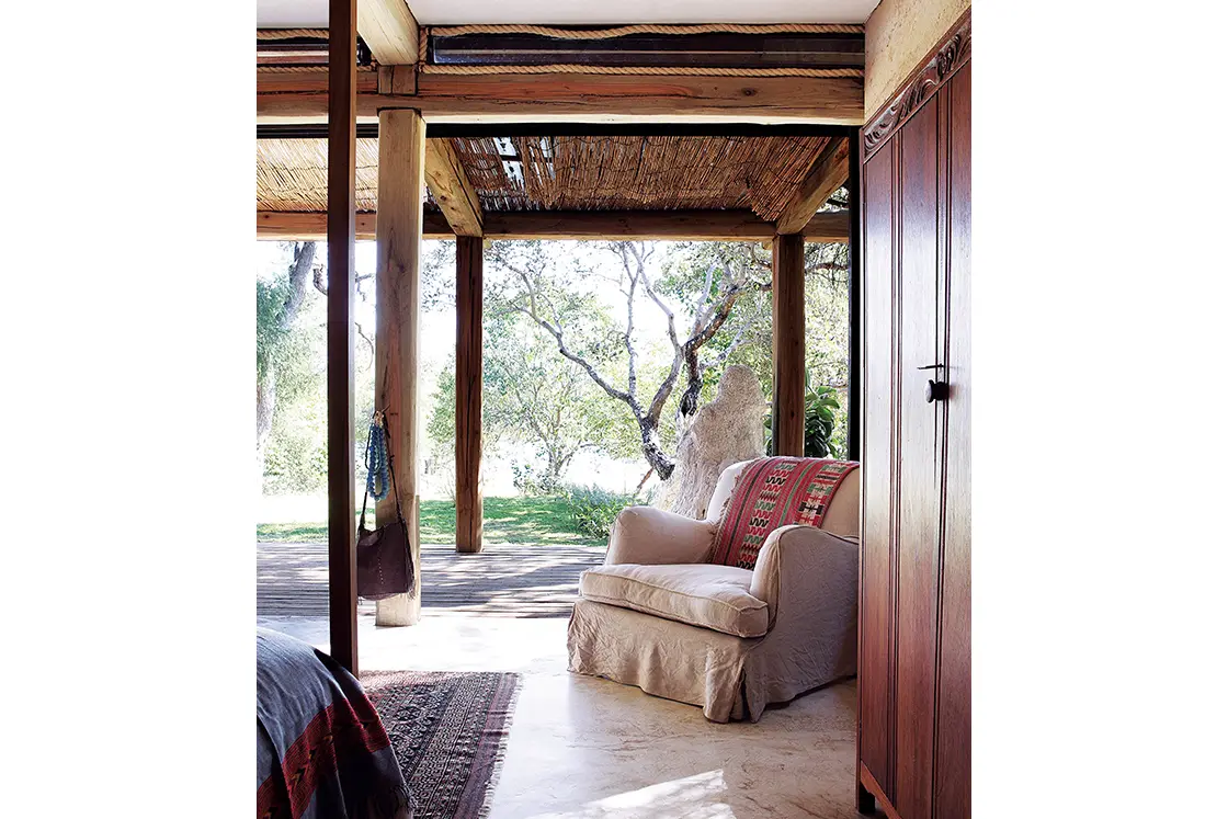 Perfect Hideaways real estate property: A patio with a pergola, featuring a comfortable chair and patterned throw. Otto House, Okavango Delta.