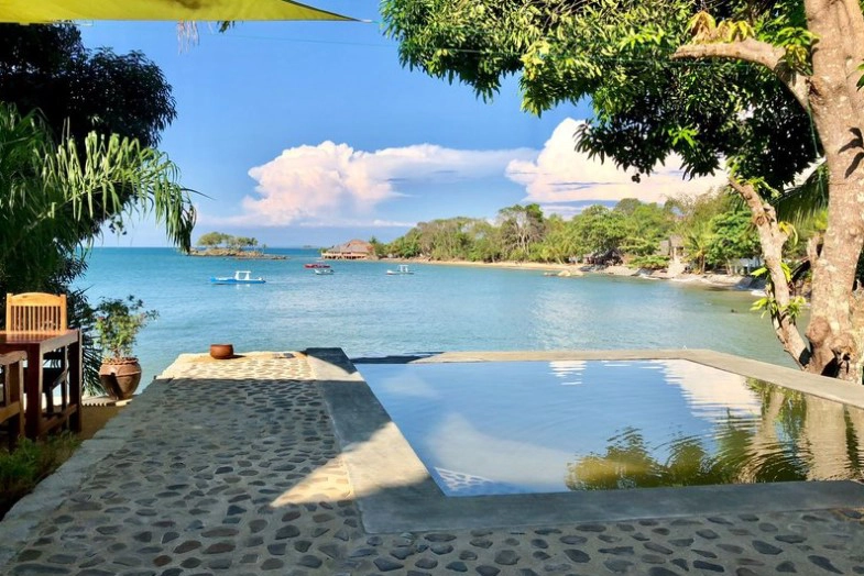 Perfect Hideaways real estate property: An outdoor deck with a swimming pool, showcasing a calm ocean bay and small fishing boats. Komba Eco Lodge, Madagascar.