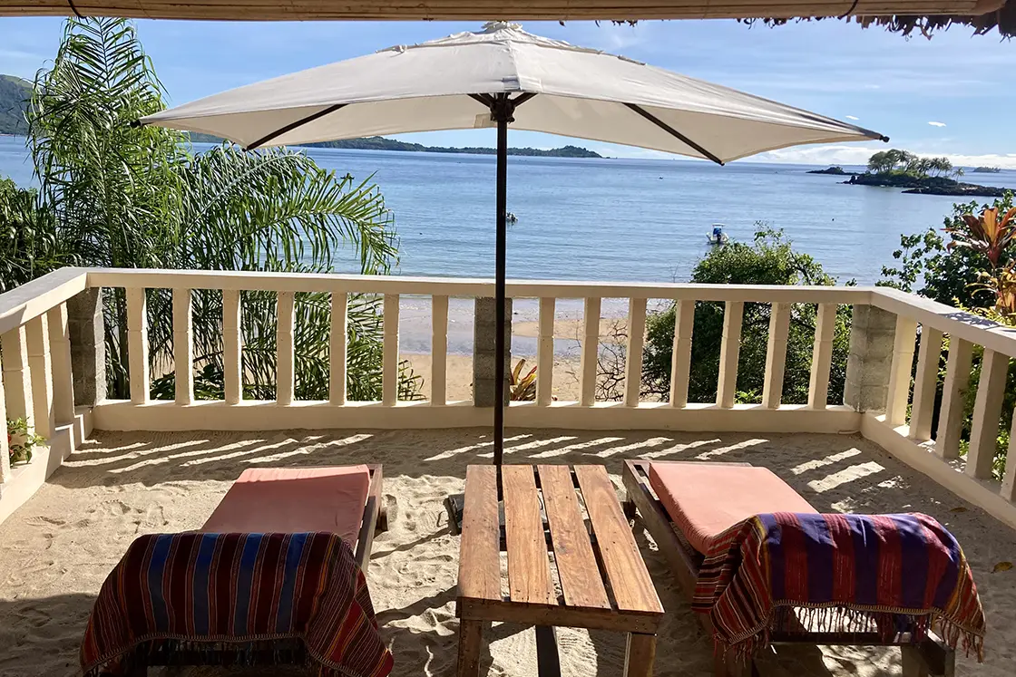 Perfect Hideaways real estate property: A balcony with sun chairs and an umbrella, featuring views of the Nosy Be island in Madagascar. Komba Eco Lodge, Madagascar.