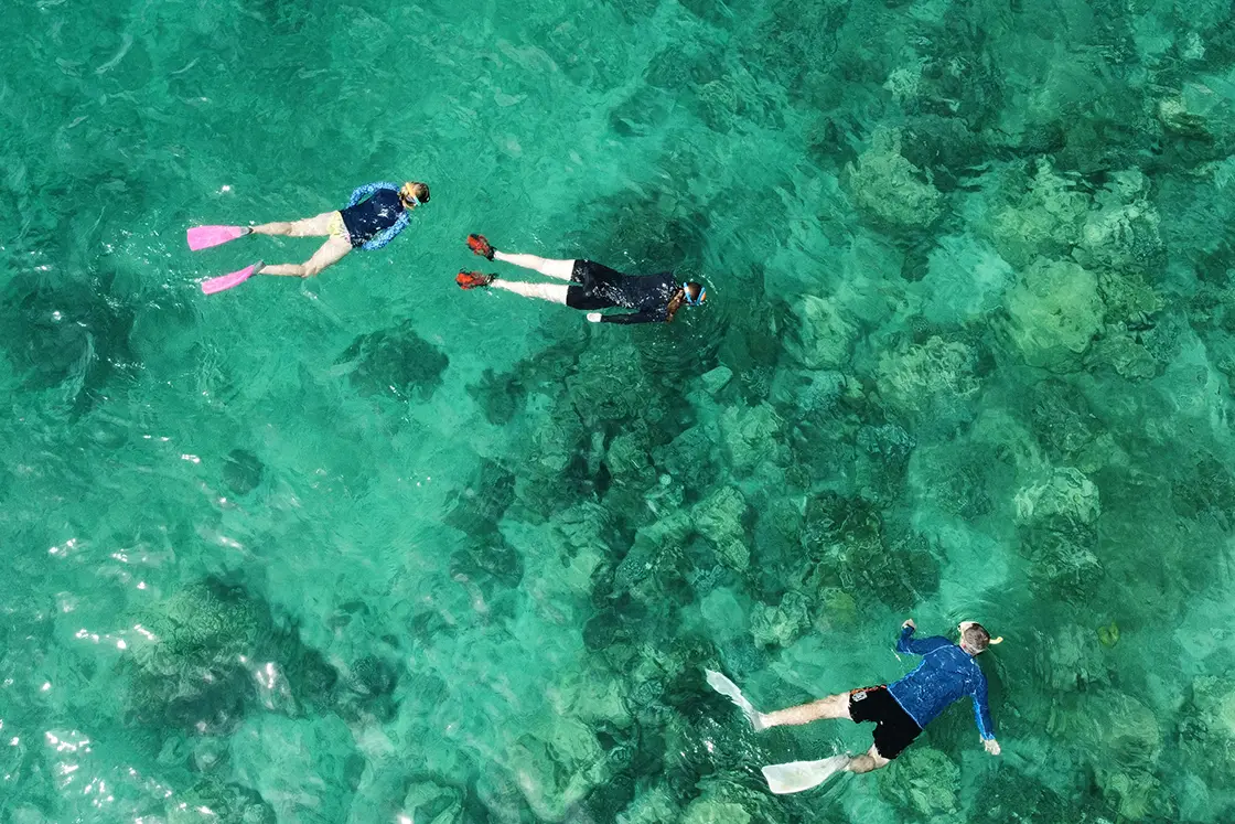 Perfect Hideaways real estate property: Swimmers snorkelling in clear blue water above a sandy reef. Komba Eco Lodge, Madagascar.