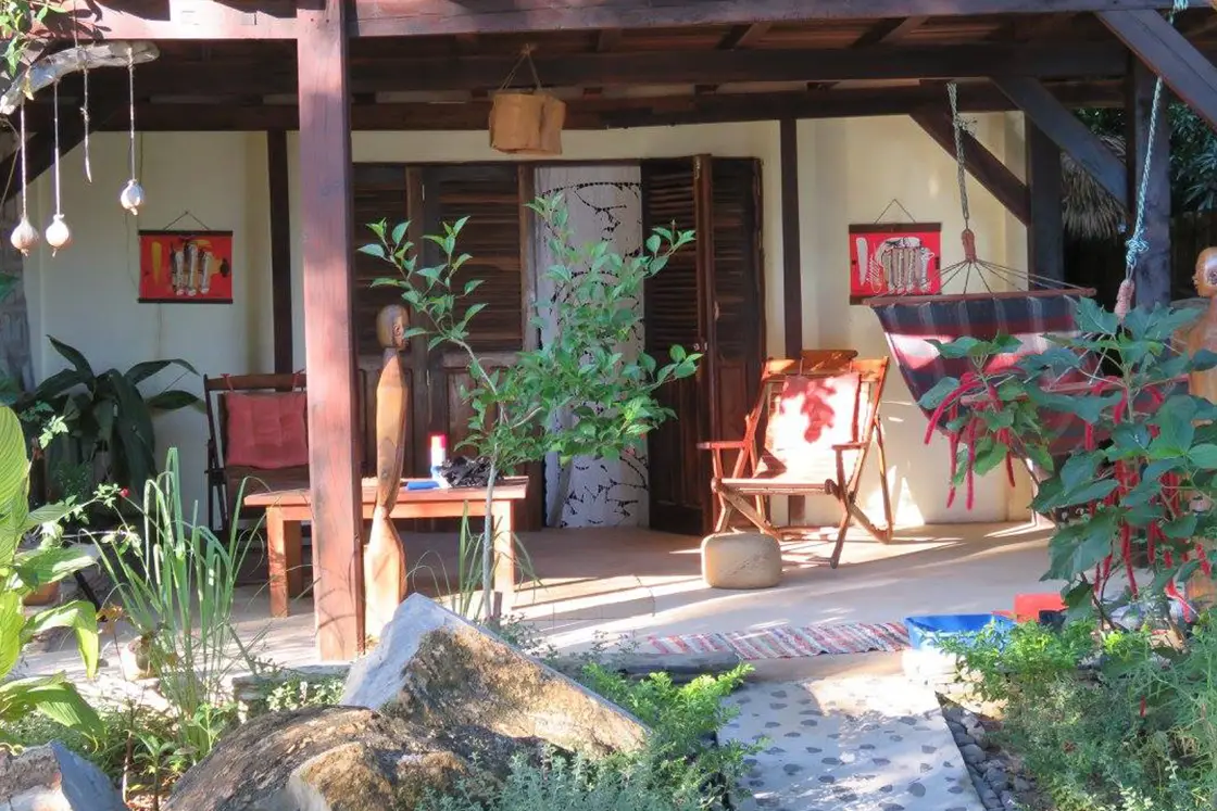 Perfect Hideaways real estate property: A patio area surrounded by lush vegetation, with wooden outdoor chairs, and a hammock. Komba Eco Lodge, Madagascar.