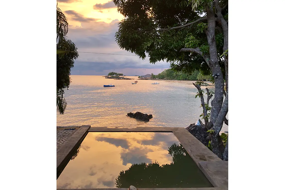 Perfect Hideaways real estate property: A clear reflection of the ocean in a pool, with views of fishing boats in a nearby bay. Komba Eco Lodge, Madagascar.