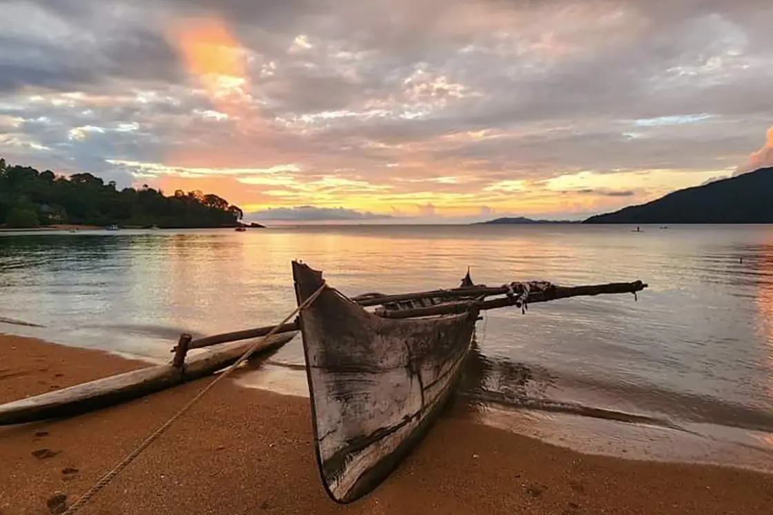 Perfect Hideaways real estate property: A tropical beach, featuring a traditional wooden fishing boat, during sunset. Komba Eco Lodge, Madagascar.