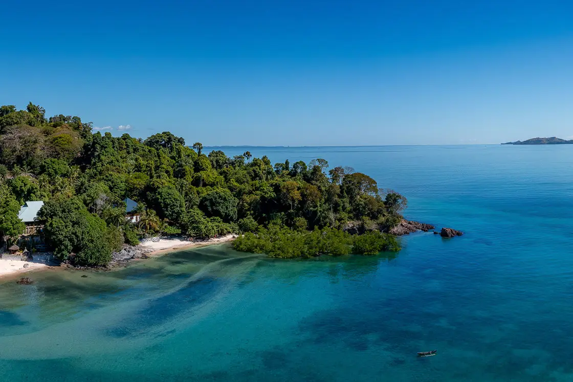 Perfect Hideaways real estate property: A tropical forest from a nearby island, surrounded by clear blue water, with islands in the background. Komba Eco Lodge, Madagascar.