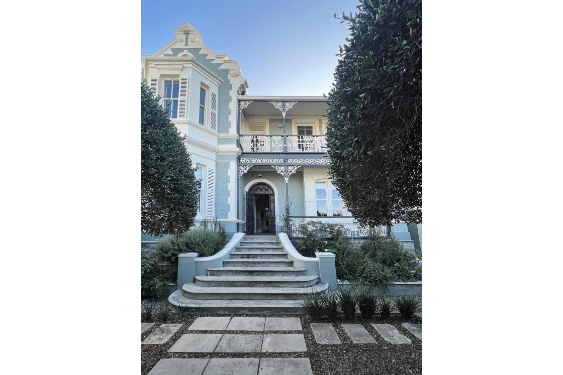 The exterior staircase leading into the house with brookie lace balcony details and turquoise coloured walls.