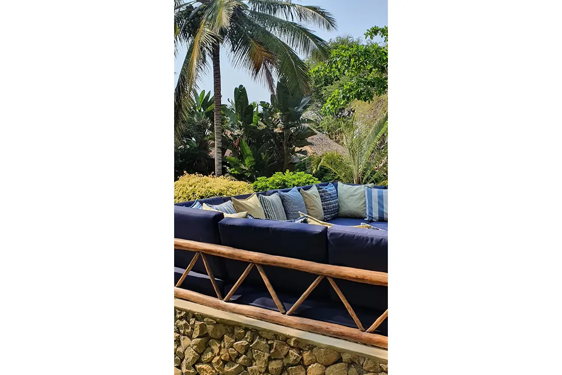 Perfect Hideaways real estate property: A navy conversation couch, featuring natural stone supporting walls, Mozambican back supports, and a variety of decorative pillows. Villa 1b Beach House, Vilanculos.