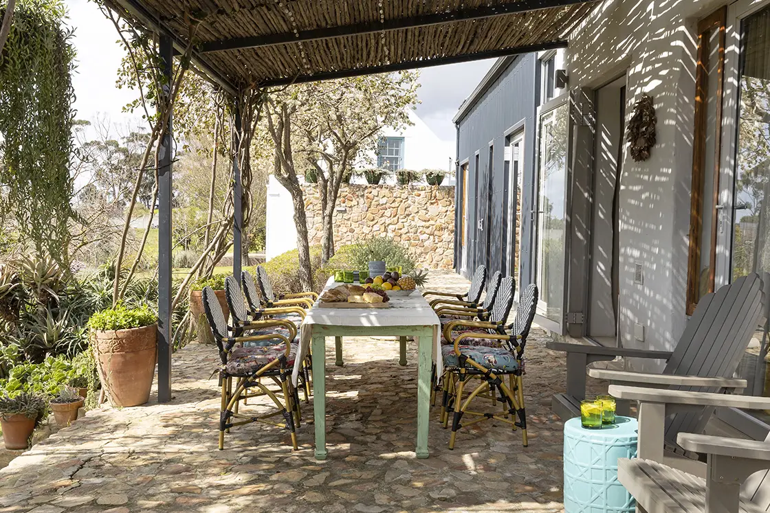 Perfect Hideaways real estate property: Veranda with natural stone floors, a dining table, featuring potted vegetation which decorates the outdoor area. Barncroft in Napier.