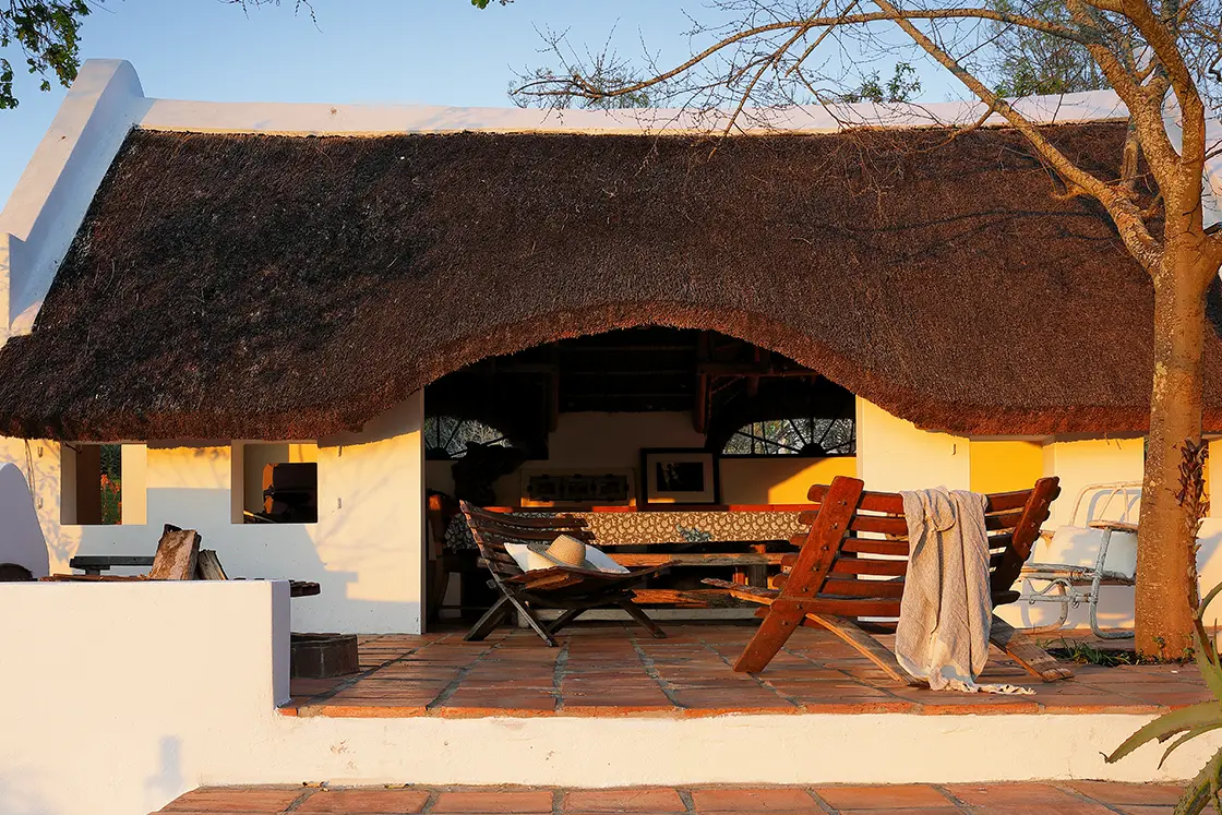 Perfect Hideaways real estate property: Thatch roof summer house with braai or outdoor fireplace, comfortable outdoor seating, and red-stone terrace. Zeekoegat Farm in Riversdale.