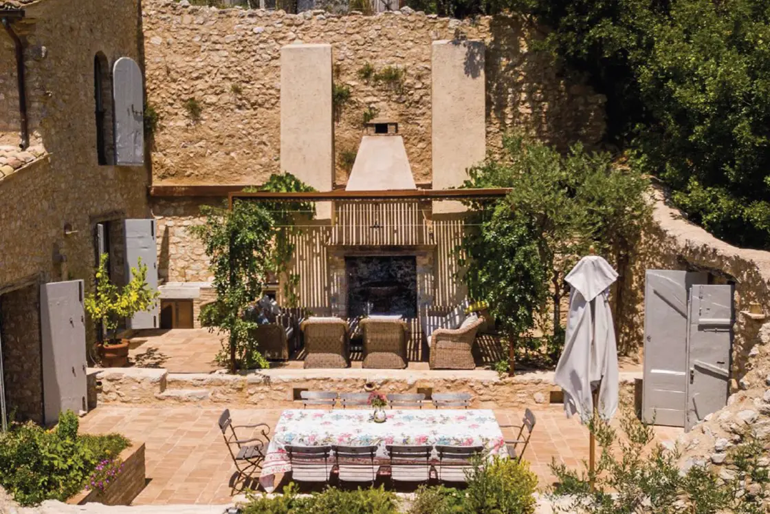 Perfect Hideaways real estate property: An Italian 'terrazzo', featuring an outdoor fireplace and dining area. Vegetation provides green accent colors to the historic natural stone villa. Casa Di Led in Spoleto.