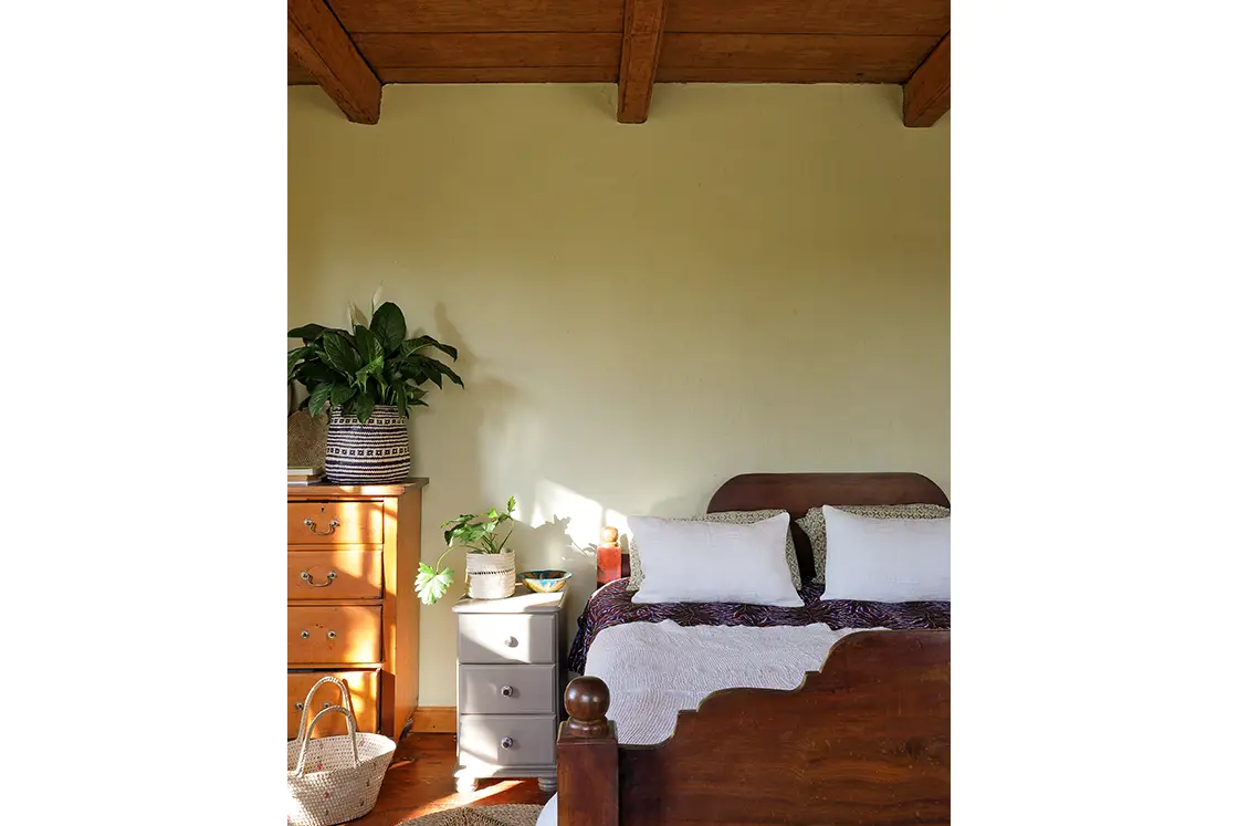 Perfect Hideaways real estate property: A bedroom area with a double bed, featuring a wooden bedframe and ceiling, with flowers decorating the room. Zeekoegat Farm in Riversdale.