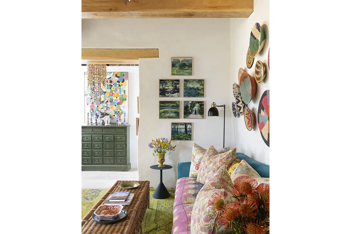 Perfect Hideaways real estate property: Navy sofa with decorative pillows beside a woven coffee table. Landscape photos and woven basket wall coverings. Barncroft in Napier.