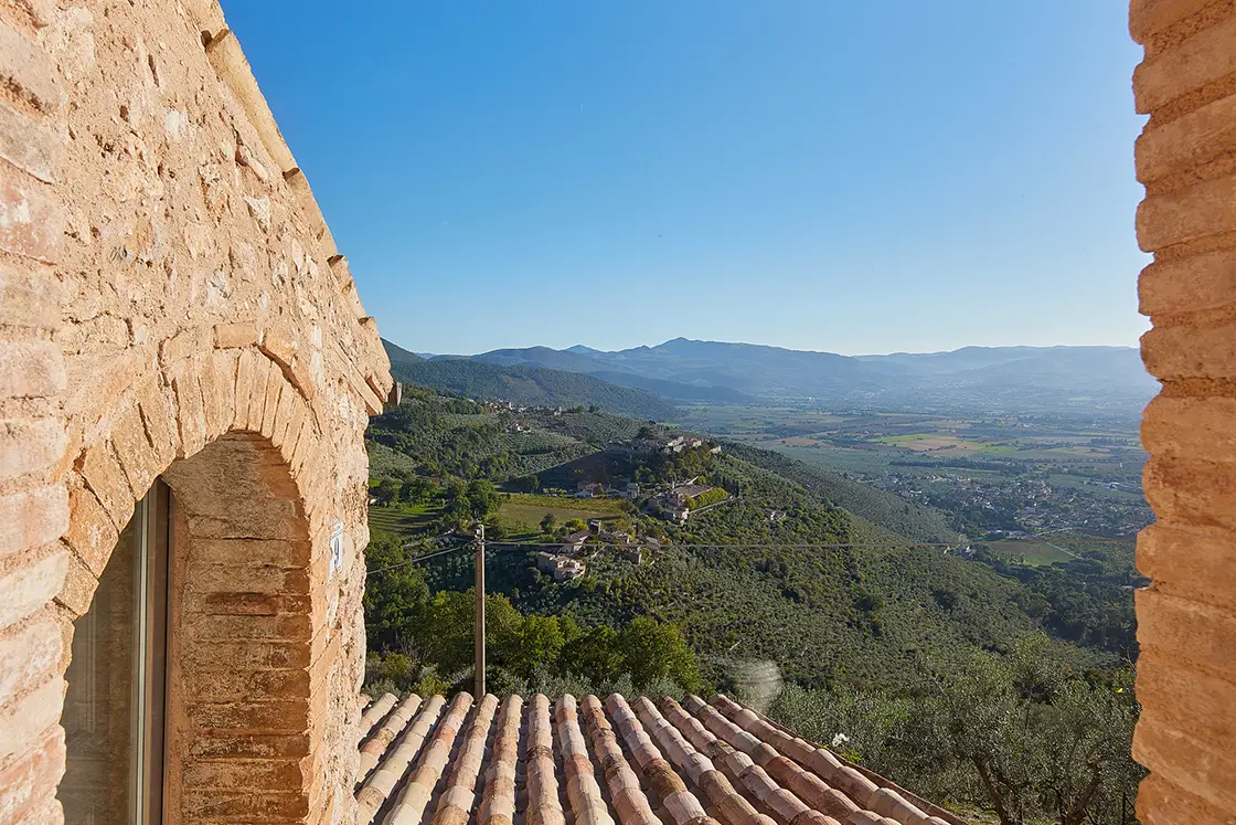 Perfect Hideaways real estate property: A natural stone arch window and terracotta roof tiling, with an elevated view of the Italian countryside. Casa Di Led in Spoleto.