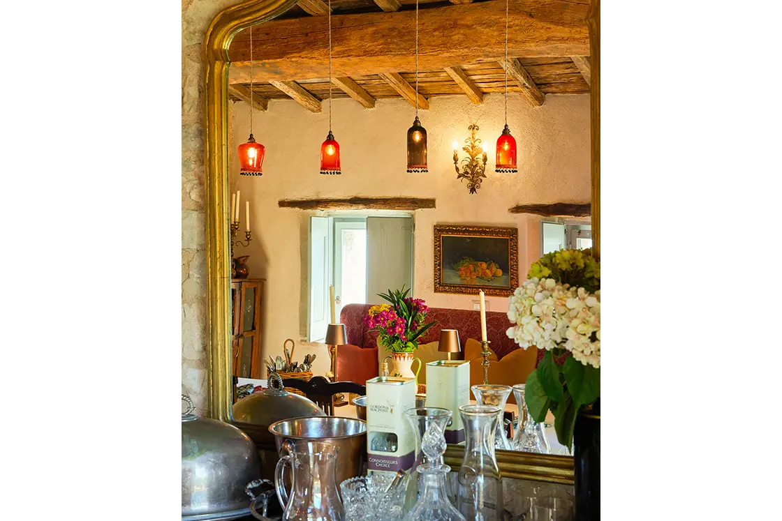 Perfect Hideaways real estate property: A gold trim mirror with the reflection of wood ceiling beams and ornate lighting, above a bar cart. Casa Di Led in Spoleto.