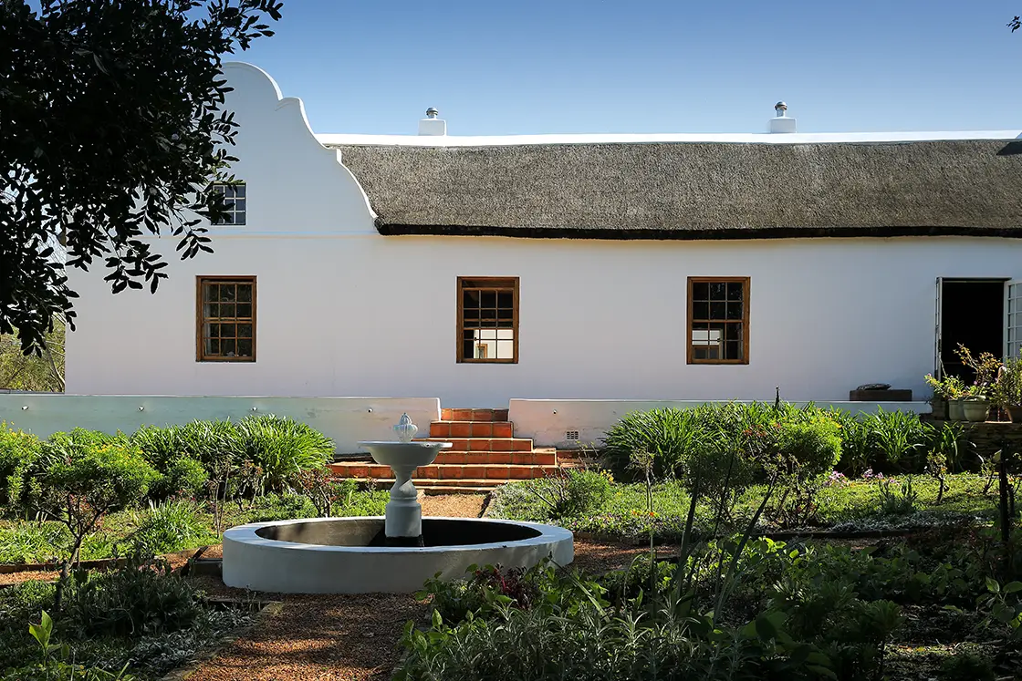 Perfect Hideaways real estate property: Garden with a central water feature and 4-way garden paths leading away, one of which ends in steps towards the main farmhouse. Zeekoegat Farm in Riversdale.