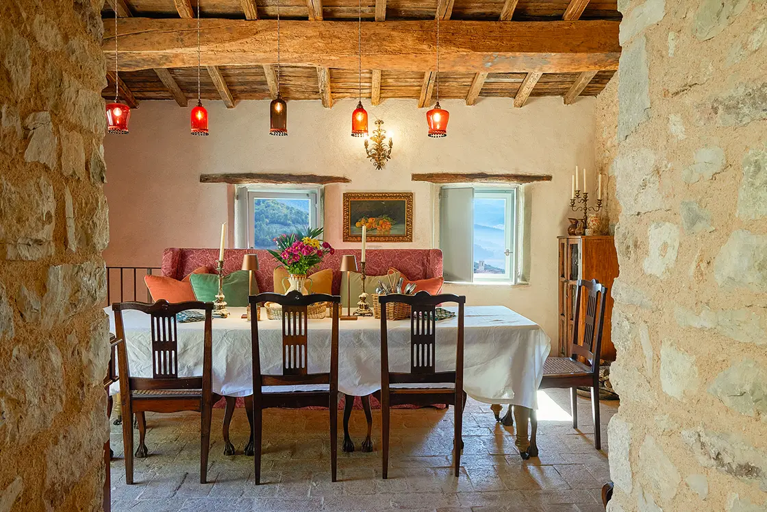 Perfect Hideaways real estate property: A natural stone doorway into the dining room. Contemporary table decoration and wooden chairs. Casa Di Led in Spoleto.