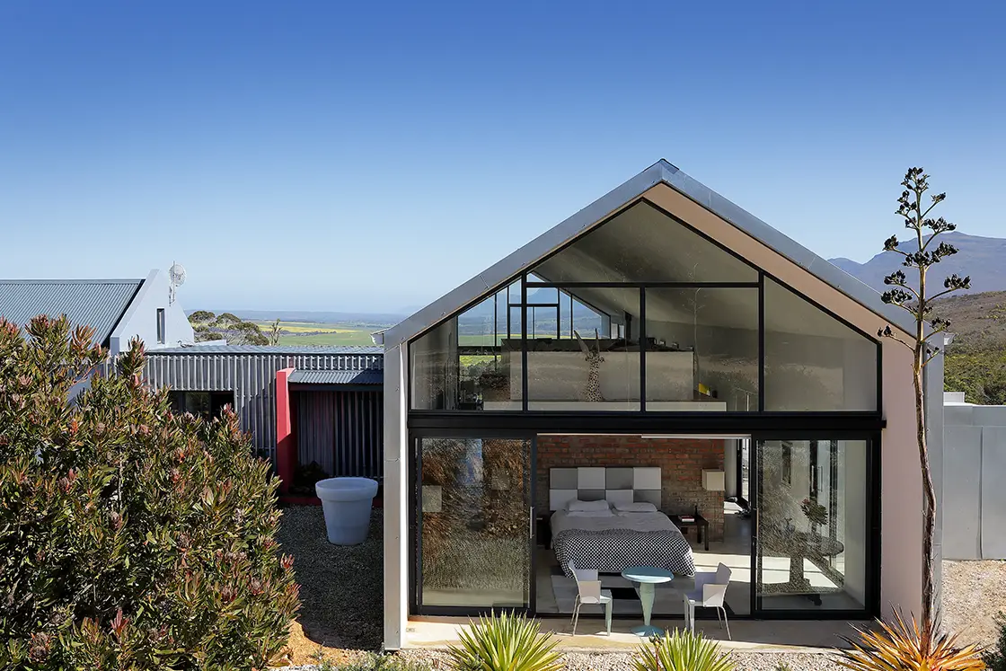 Perfect Hideaways real estate property: A frame-house nestled among lush trees and green grass, with a backdrop of mountains. HaesFarm in Stanford.