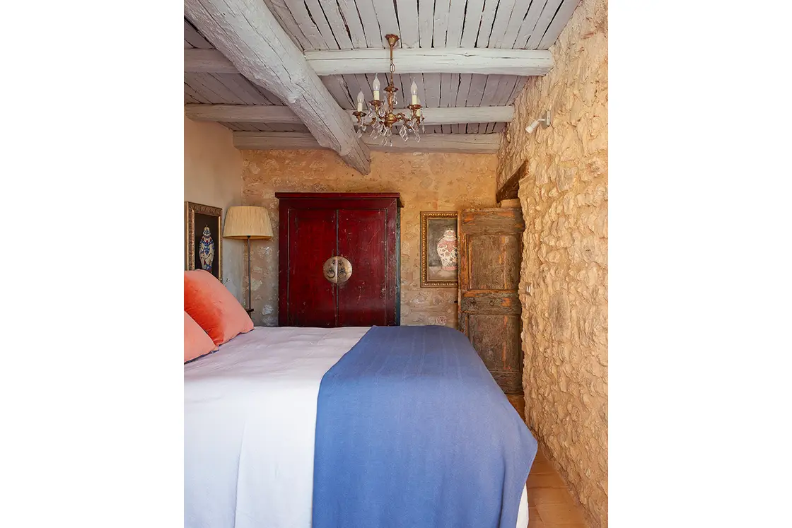 Perfect Hideaways real estate property: A bedroom area, showcasing an ornamental red cupboard and authentic aged-wood door. Natural stone and lime wash interior. Casa Di Led in Spoleto.