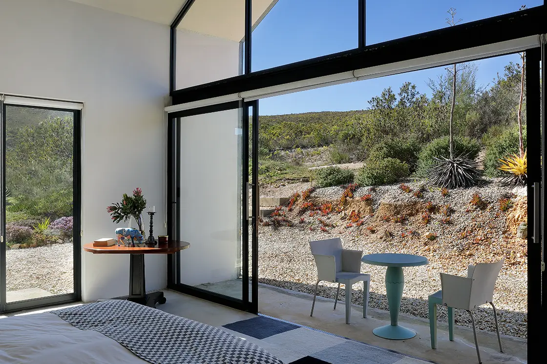 Perfect Hideaways real estate property: A modern bedroom featuring large windows that reveal a view of a natural garden. HaesFarm in Stanford.