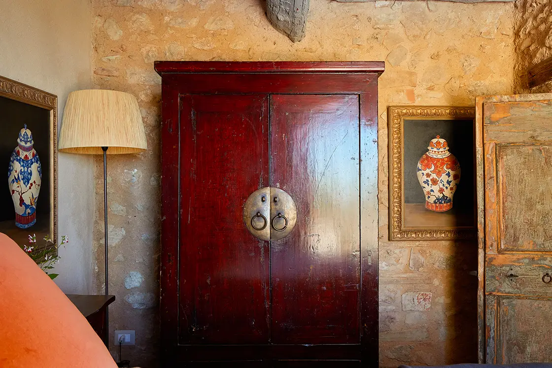 Perfect Hideaways real estate property: A bedroom area, featuring an ornamental red cupboard, and authentic aged-wood door. Decorative gold-trim paintings. Casa Di Led in Spoleto.