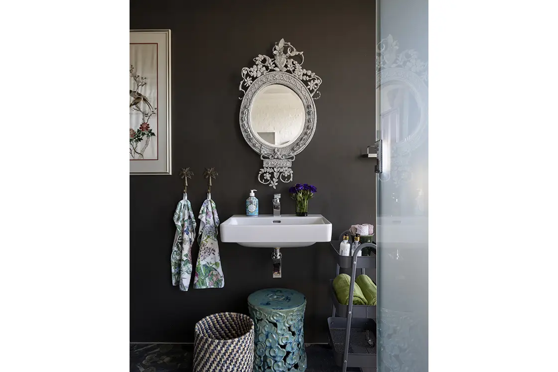 Perfect Hideaways real estate property: A bathroom with a floating basin and mirror against a matte black wall, and a mobile bathroom storage unit. Barncroft in Napier.