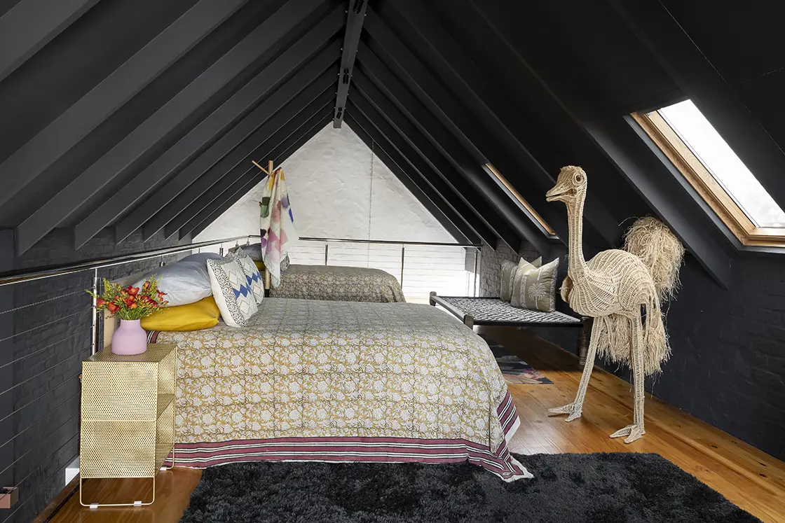 Perfect Hideaways real estate property: An attic loft space with a double bed, a single bed, and a skylight. Black tuft rug, a lounger, and a beaded ostrich sculpture. Barncroft in Napier.