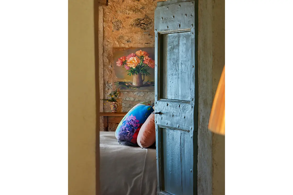 Perfect Hideaways real estate property: An open door looking into a bedroom with a natural stone wall, featuring a floral painting. Casa Di Led in Spoleto.