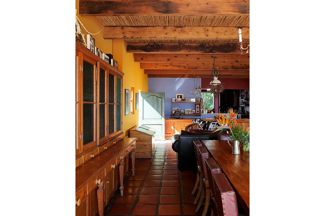 Perfect Hideaways real estate property: Living room view with leather chairs, wooden joinery, and terracotta floors. Blue and orange walls. Zeekoegat Farm in Riversdale.