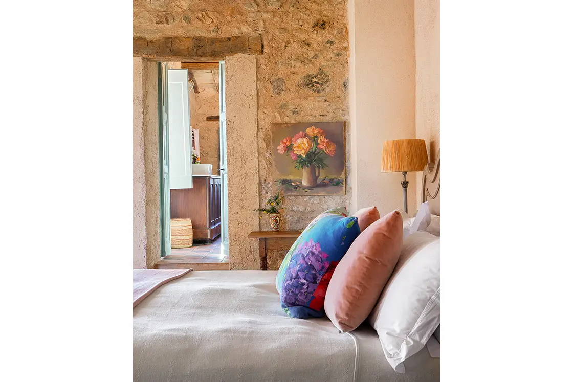 Perfect Hideaways real estate property: A bedroom with an en-suite bathroom and rustic decor. Ornate lamp shade and muted pink tones create a comforting atmosphere. Casa Di Led in Spoleto.