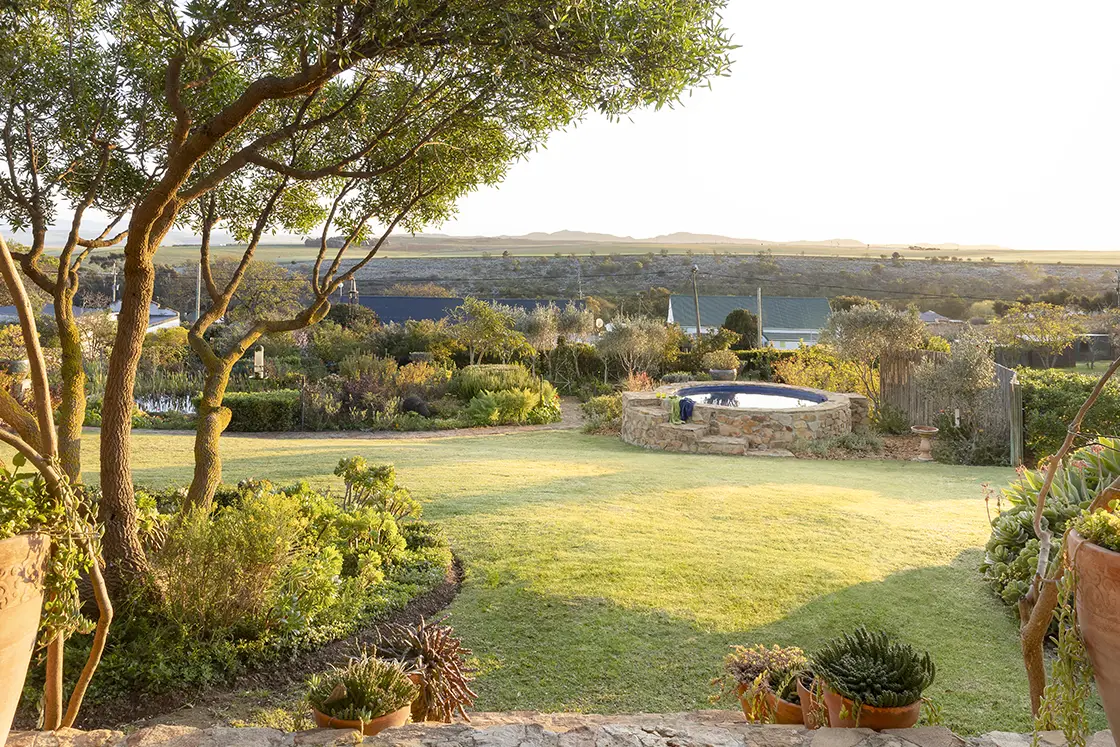 Perfect Hideaways real estate property: A sunset garden view from the porch area, as well as an outdoor pool with mountains on the horizon. Barncroft in Napier.