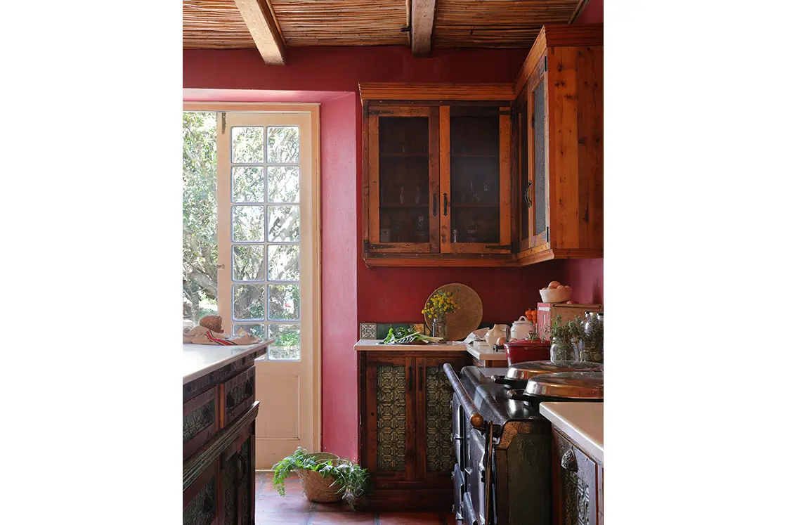 Perfect Hideaways real estate property: Kitchen with red walls, cupboards sit above refurbished countertops. A four-door Aga stove is set against the wall. Zeekoegat Farm in Riversdale.