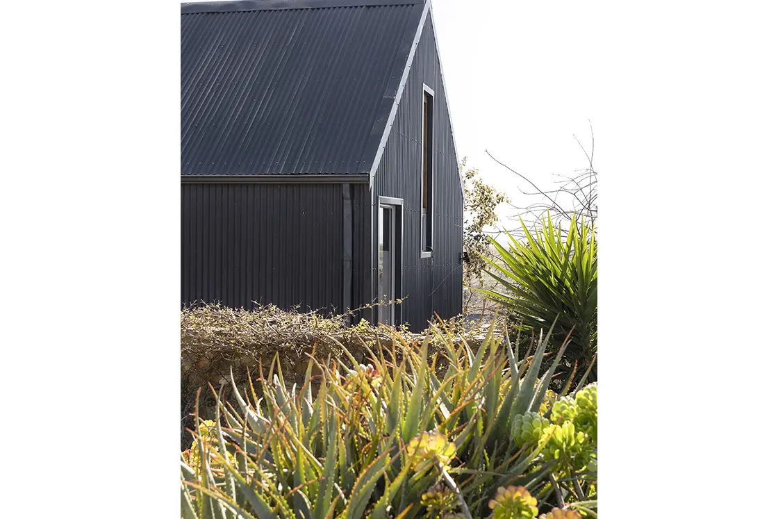 Perfect Hideaways real estate property: A side view of the barn-style home, featuring black corrugated roofing, as seen from the garden. Barncroft in Napier.