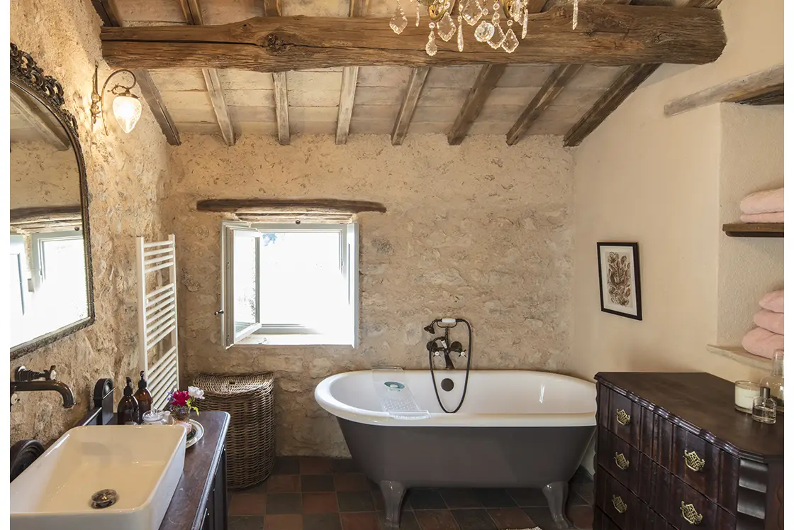 Perfect Hideaways real estate property: A bathroom, featuring checkerboard tiles and wooden drawers, as well as a two-tone bathtub beside a shuttered window. Casa Di Led in Spoleto.