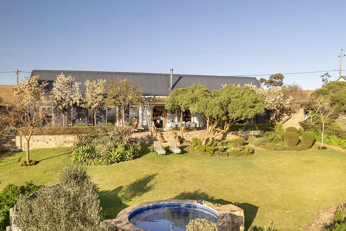 Perfect Hideaways real estate property: Select vegetation separates the grass lawn, highlighting a garden pool and open-view veranda. Barncroft in Napier.