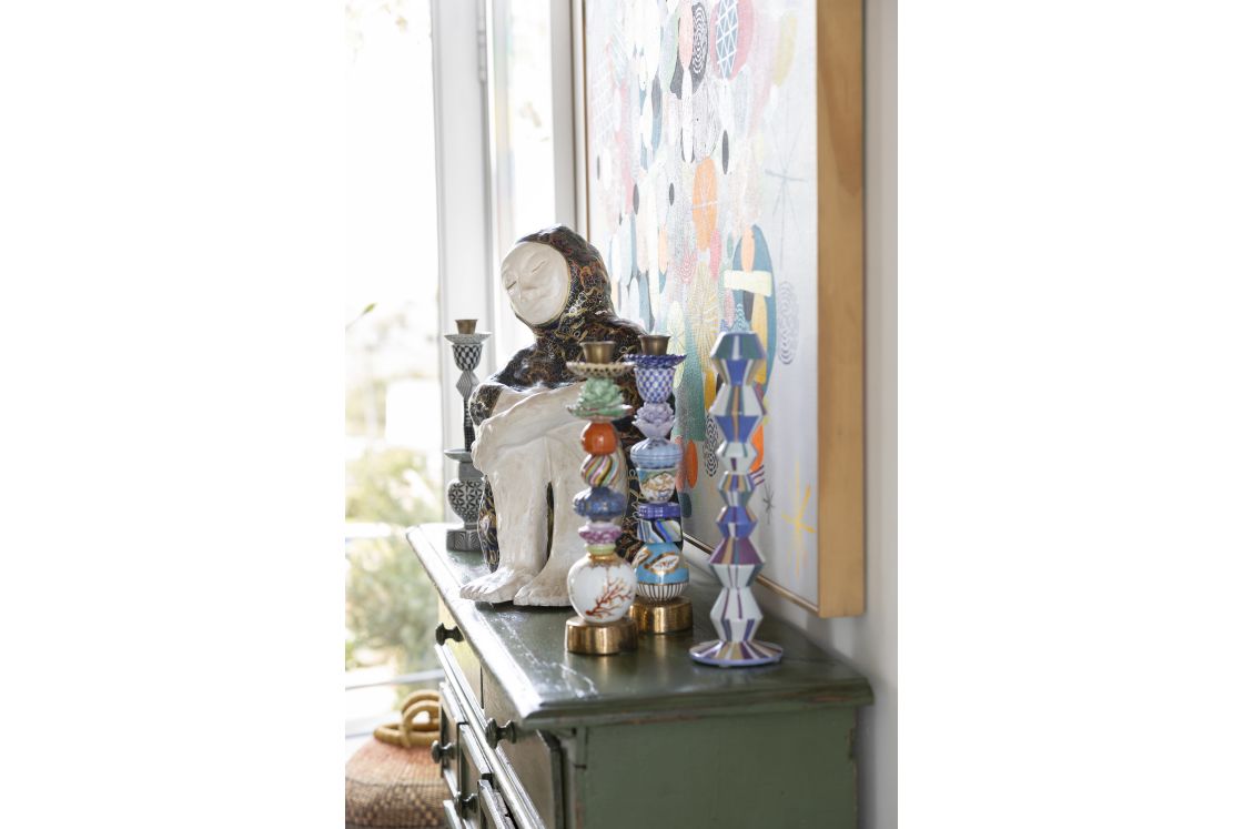 Chest of drawers with decorative statue, candle holders, and wall painting. Overberg.