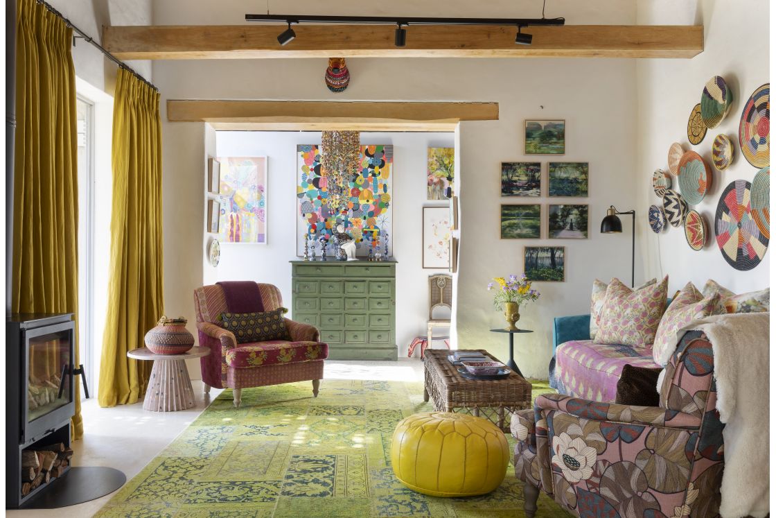 Living room with contemporary furnishings, low ceiling beams, thick curtains, and indoor fireplace. Overberg.