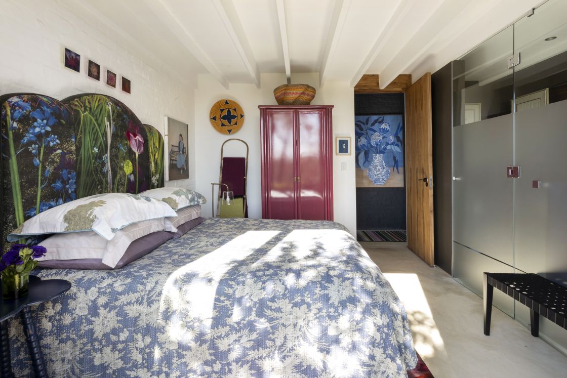 Double bedroom with en-suite bathroom. Blue and purple tones complement white brick wall. Overberg.