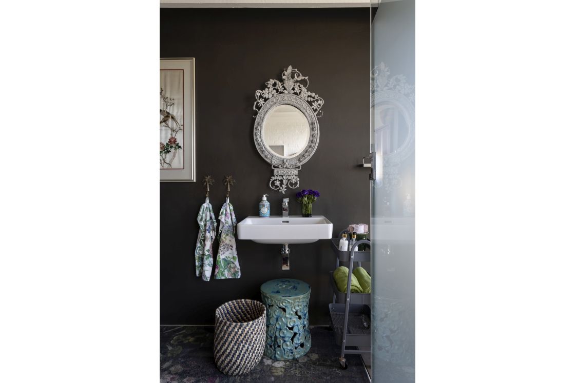 Pale basin and mirror against matte black wall. Mobile bathroom storage unit. Overberg.