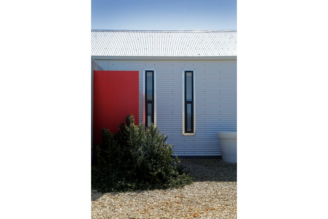 The iron white house showcasing a bold red door and black window trim.