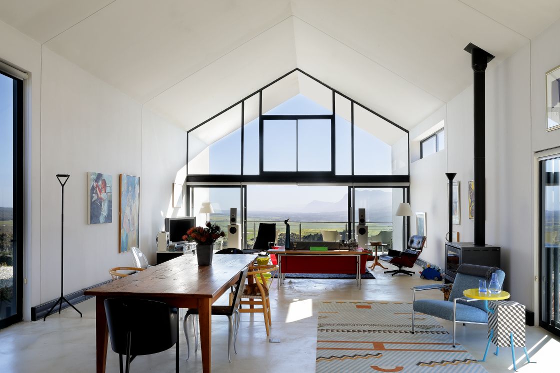 A spacious living room featuring a large window that a central table and lounge area with contemporary furniture.