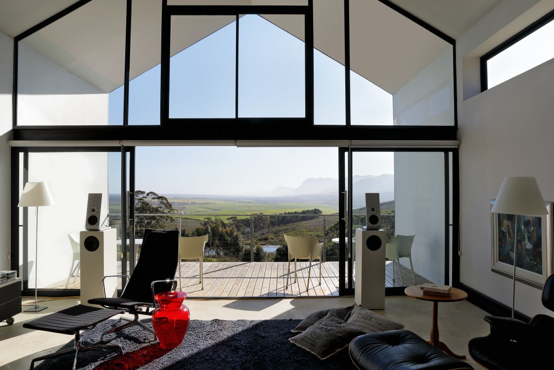 A modern living room with wide windows that frame a beautiful valley scene outside.