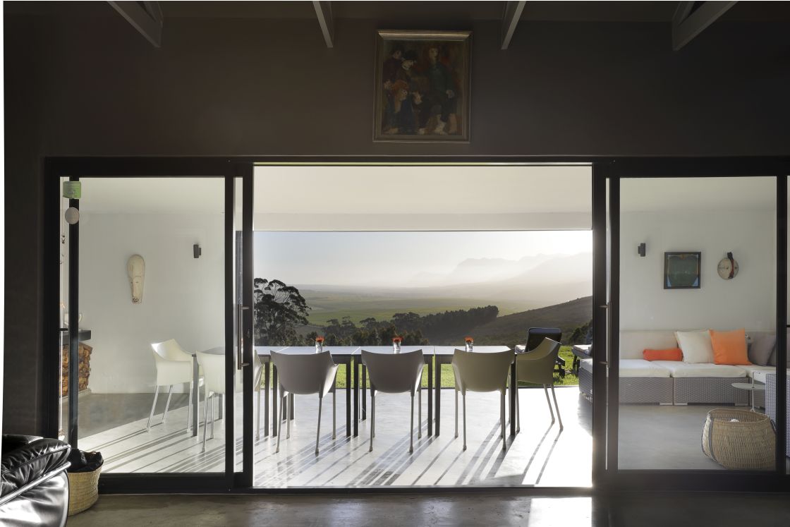 A view from inside a house showcasing the exterior landscape through a window and a outdoor dining area.