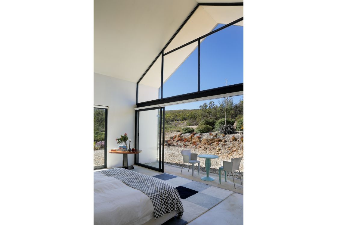 The bedroom showcases a large glass wall, providing a view of the front garden.