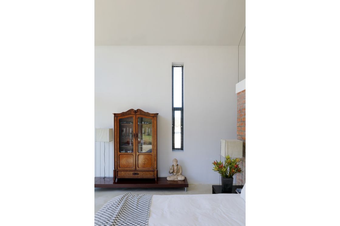 A tranquil bedroom highlighted by a small window and wooden cabinet.