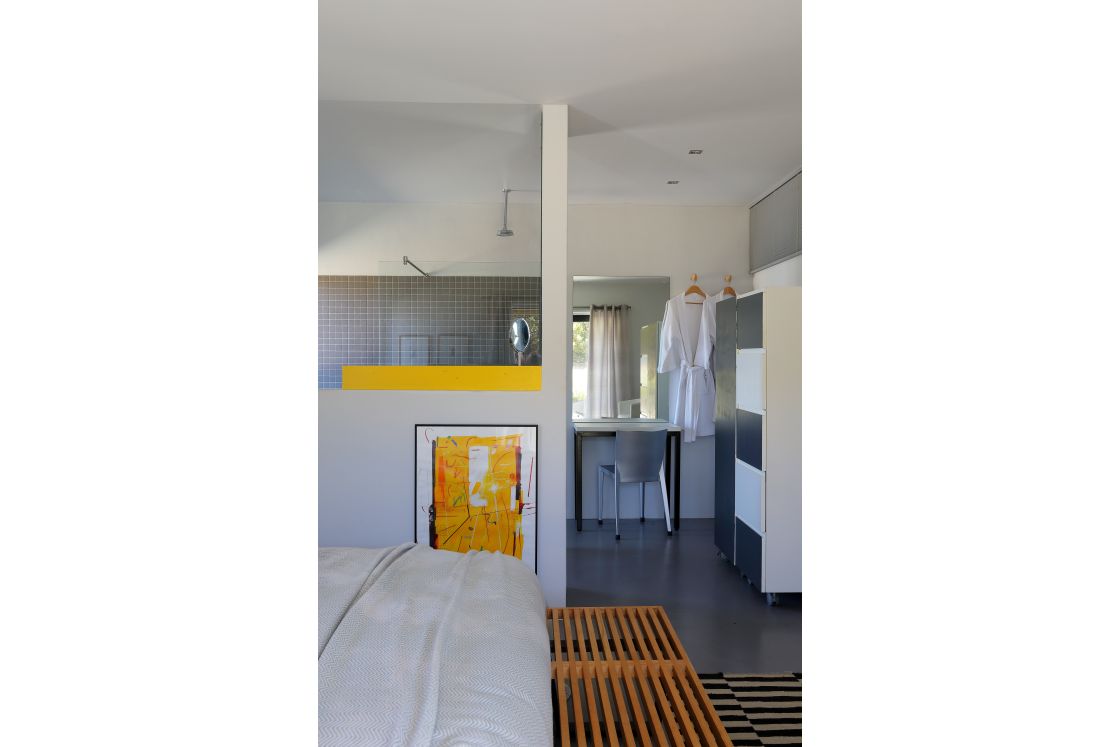 A bedroom with a plush bed, a reflective mirror, and an artistic painting and en-suite bathroom.