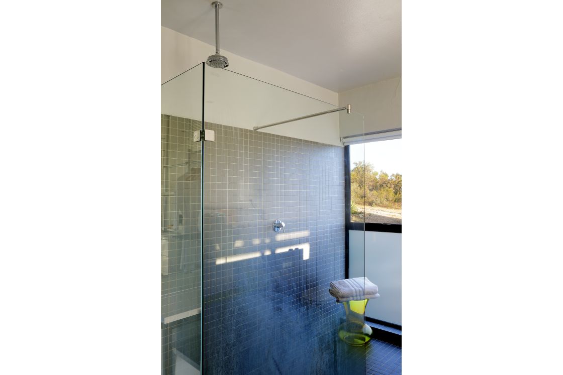 A modern bathroom featuring a glass shower enclosure and a window looking out landscapes.