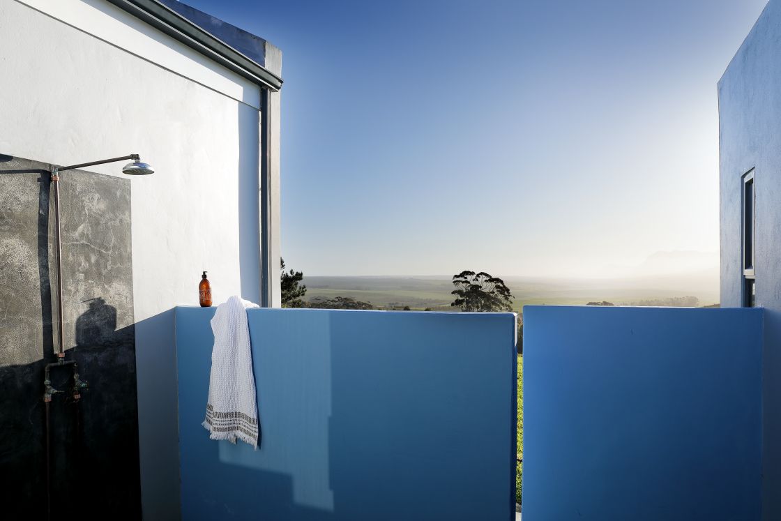 An outdoor shower with a view of the mountain range and valley.