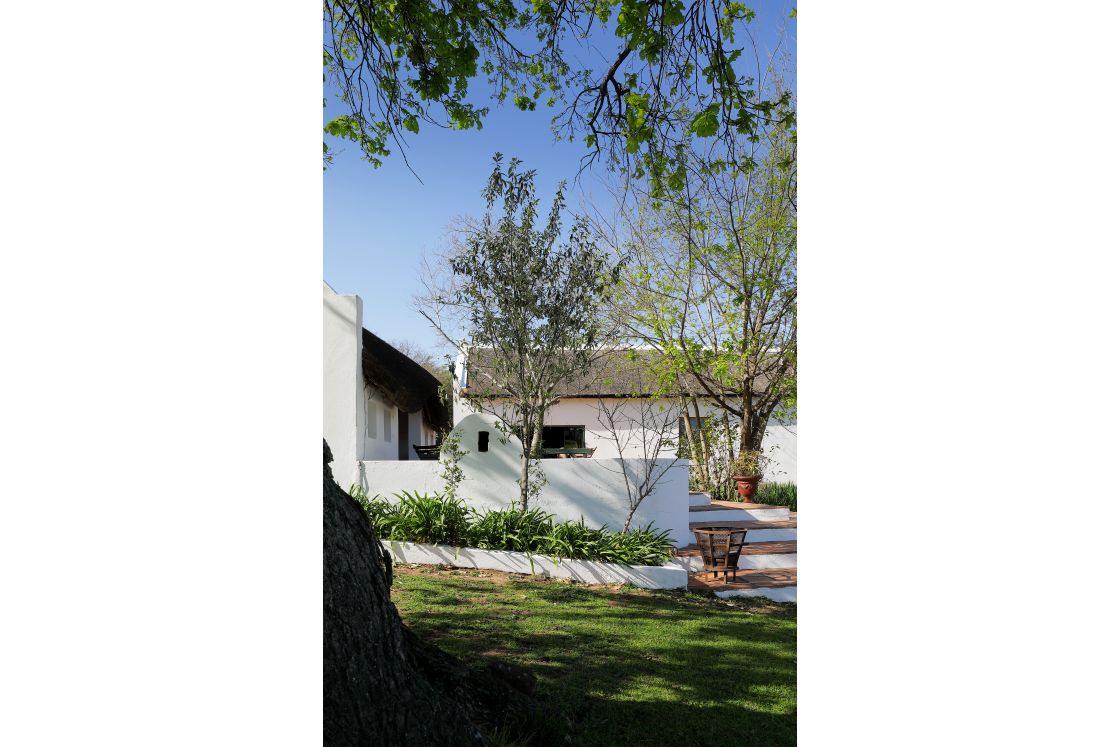 Main farm style home as seen from the garden, short flight of stairs lead from the grass to nearby veranda.