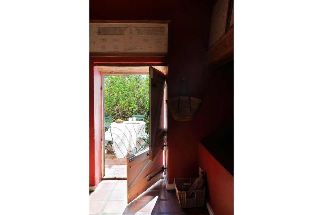 Barn-style door and red walls in the Historic National-Monument House, a small sunlit coffee table outside.