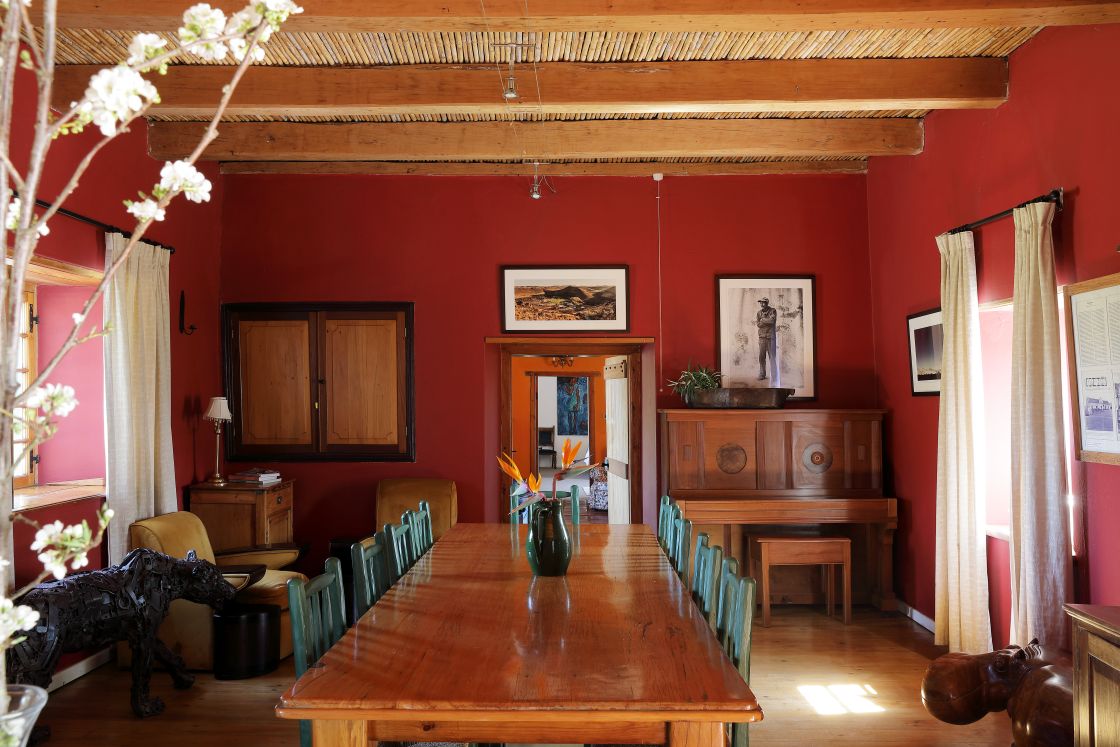 Dining room with red walls, long dining table, animal statues, and farm style decor.